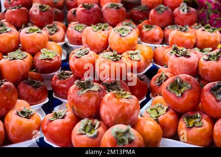 Persimmons freschi maturi nel mercato. Sfondo dei persimmons. Frutta di persimmon biologica in mucchio al mercato locale degli agricoltori. Sfondo dei persimmons. Primo piano Foto Stock