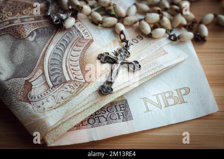 finanze della chiesa, il concetto di finanziamento di una chiesa in Polonia, pagamento a un sacerdote per un carol un pacchetto di banconote e un rosario Foto Stock