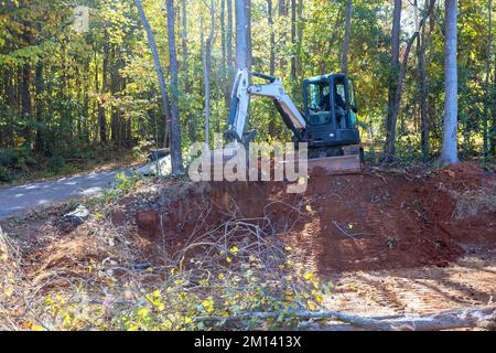 Lo sradicamento degli alberi e la preparazione del terreno per la costruzione vengono eseguiti con il trattore Foto Stock