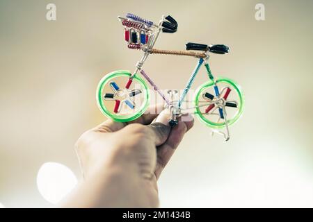 Uomo in possesso di un giocattolo verde ciclo colore prodotto a mano con giocattoli in alluminio per bambini in colore verde vendita in mercato, fiera, centro commerciale, o negozio Foto Stock