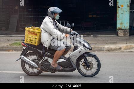 SAMUT PRAKAN, THAILANDIA, 21 2022 MAGGIO, Un uomo cavalca una moto con carico per strada Foto Stock