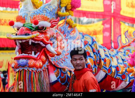 Bangkok, Thailandia. 10th Dec, 2022. Un uomo si trova accanto a una statua di un drago durante il festival Chao Por-Goddess nel quartiere di Chum Sang, Bangkok. La grande danza del Monte Liang Shan, è una danza tradizionale cinese che combina musica, danza e arti marziali eseguite da 108 ballerini che dipingevano i loro volti in diversi personaggi basati sulla storia del gregge cinese. Il famoso festival annuale è stato fondato per la prima volta nel 1947 per rispettare il Santuario di Chao Por-Goddess. Lo spettacolo consiste in una processione di attori sfilati intorno al distretto di Chum Sang. Provincia di Nakhon Sawan, acrobazie e arti marziali pe Foto Stock