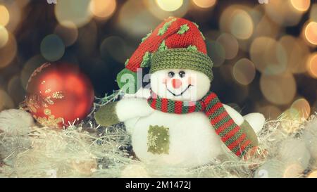 Pupazzo di neve festivo con sfondo di luce di Natale. bellissimo effetto bokeh da una ghirlanda. Foto Stock