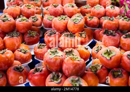 Persimmons freschi maturi nel mercato. Sfondo dei persimmons. Frutta di persimmon biologica in mucchio al mercato locale degli agricoltori. Sfondo dei persimmons. Primo piano Foto Stock