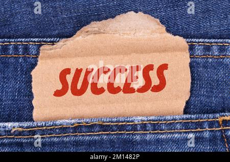 Affari e finanza. Una scatola di cartone con l'iscrizione-SUCCESSO si stacca da jeans. Foto Stock