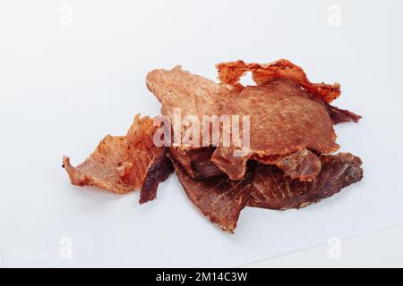 Primo piano di un uomo anziano affettando con cura un tenero brisket di manzo stagionato da servire in un ristorante barbecue. su sfondo bianco. Foto di alta qualità Foto Stock