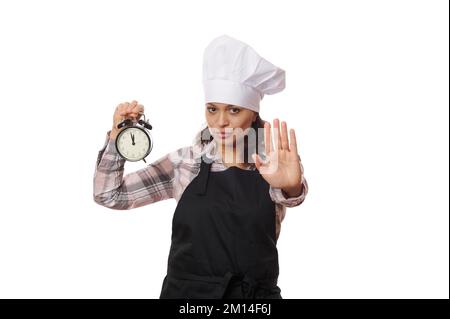 Cameriera femminile, operatrice di caffè in grembiule nero con sveglia, che estende la sua mano per mostrare stop o proibizione gesto Foto Stock