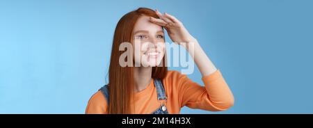 Ragazza guardare lontano distanza girare a sinistra tenere mano fronte di copertura gli occhi caldi luce del sole che sorridevano deliziati a guardare erano palla caduta peer afar gioiosamente squinting ottenere Foto Stock