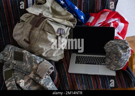 Zaino e laptop contro la bandiera americana. Educazione militare Foto Stock