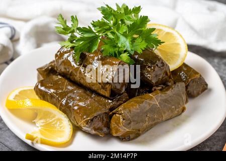 Foglie farcite con olio d'oliva o dolma su fondo scuro. Cucina turca sapori antipasto. primo piano Foto Stock