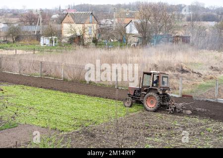 il trattore agricolo con aratro arpa il campo e si prepara alla semina. Foto Stock