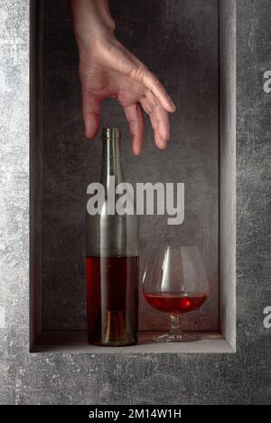 Sbraccio a mano per un decanter di brandy. Un'immagine concettuale sul tema delle bevande costose. Foto Stock