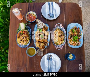 Tavolo per la cena con piatti thailandesi e pesce alla griglia sulla spiaggia di Pattaya Thailandia. Foto Stock