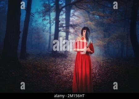 Donna sciamano in una foresta mistica profonda, con un ventilatore di piume e una corna di cervo in mano. Ventilatore di piume usato per osservare durante le cerimonie. Foto Stock