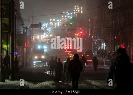 2022-12-08 Kiev, Ucraina. La silhouette dei pedoni nella nebbiosa città notturna. Blackout a Kiev Foto Stock