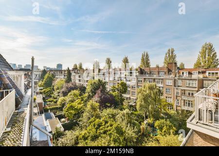 un appartamento con alberi ed edifici sullo sfondo, preso dalla nostra finestra balcone che si affaccia sulla città sottostante Foto Stock