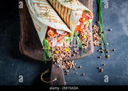 Tortilla vegetariana deliziosa e fresca con semole, pomodori ciliegini e erba cipollina. Tortilla vegetariana con verdure. Foto Stock