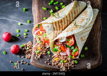 Tortilla vegetariana deliziosa e fresca con semole, rafano e pomodori ciliegini. Tortilla vegetariana con verdure. Foto Stock