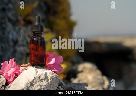 Medicinali da Bach fiori, bottiglia con contagocce in ambiente naturale. Simulazione. Bel mockup floreale per la presentazione di cosmetici, produzione medica. Foto Stock