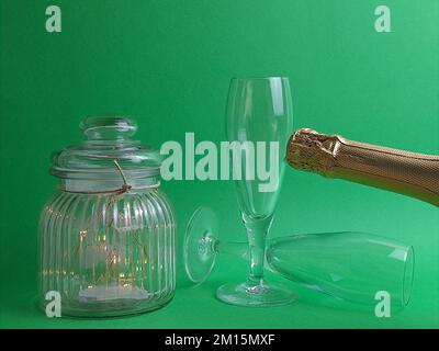 Capodanno una bottiglia di vino frizzante in vetro verde e dorato con bicchieri, calici. Biglietti d'auguri per il Capodanno, con piccole luci. Foto Stock