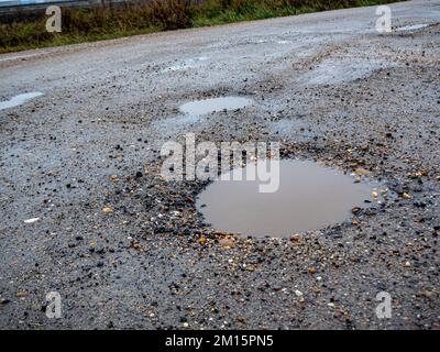 In prossimità di grandi buche con sporco acqua di pioggia della strada. Foto Stock