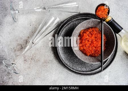 Da sopra il caviale di pesce trota fresco rosso servito in una ciotola su fondo di tavolo di cemento Foto Stock