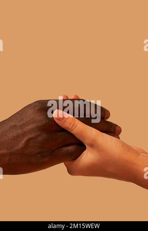 Crop anonimo afroamericano uomo tenendo le mani con la donna in studio vicino sfondo rosa Foto Stock