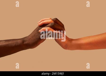 Crop anonimo afroamericano uomo tenendo le mani con la donna in studio vicino sfondo rosa Foto Stock