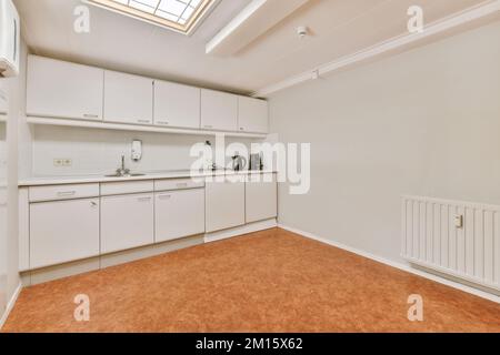 Frammento di interno di piccola cucina domestica con stile minimalista mobili bianchi con lavandino e stufa Foto Stock