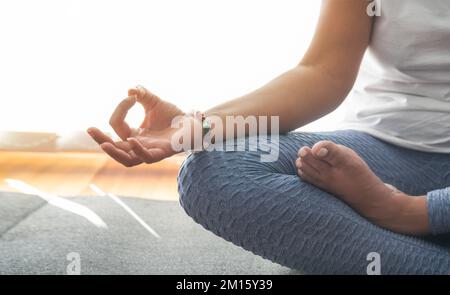 Donna anonima gesturante Gyan mudra e meditating in Lotus posa durante la sessione di yoga la mattina presto a casa Foto Stock