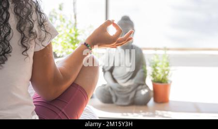 Donna anonima gesturante Gyan mudra e meditating in Lotus posa durante la sessione di yoga la mattina presto a casa Foto Stock