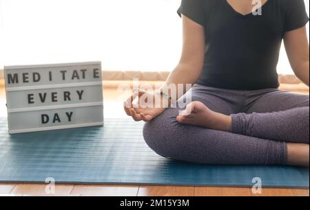 Donna anonima gesturante Gyan mudra e meditating in Lotus posa durante la sessione di yoga la mattina presto a casa Foto Stock