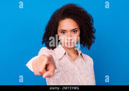 Foto della calma messa a fuoco donna d'affari che punta la macchina fotografica del dito che avete isolato su sfondo di colore blu Foto Stock