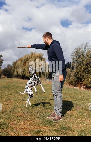 bel giovane uomo con cane all'aperto. un uomo su erba verde con un cane. cinologo Foto Stock