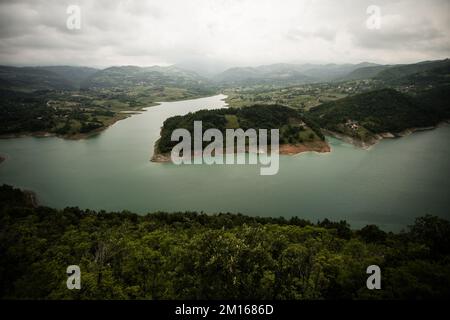 Una vista aerea del Lago di Rovni circondato da una vegetazione verde sotto il cielo grigio nuvoloso nella Serbia occidentale Foto Stock