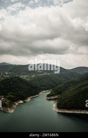 Una vista aerea del Lago di Rovni circondato da una vegetazione verde sotto il cielo grigio nuvoloso nella Serbia occidentale Foto Stock