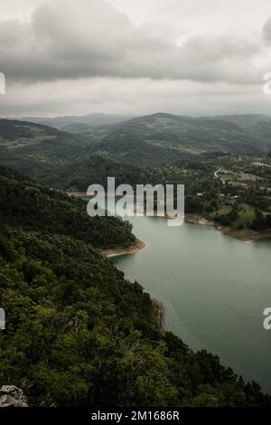 Una vista aerea del Lago di Rovni circondato da una vegetazione verde sotto il cielo grigio nuvoloso nella Serbia occidentale Foto Stock