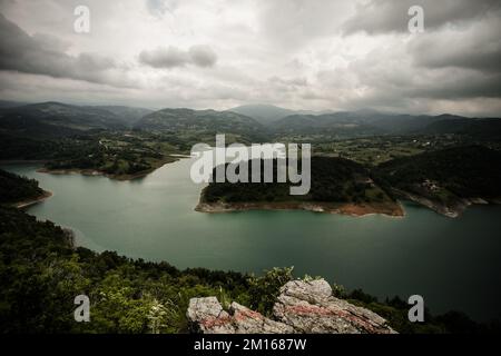 Una vista aerea del Lago di Rovni circondato da una vegetazione verde sotto il cielo grigio nuvoloso nella Serbia occidentale Foto Stock