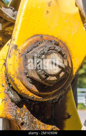 primo piano di un giunto giallo sul braccio di un escavatore con pala con molto grasso Foto Stock