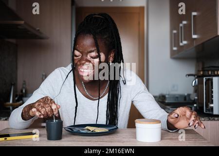 Felice donna nera che fa colazione sana in cucina Foto Stock