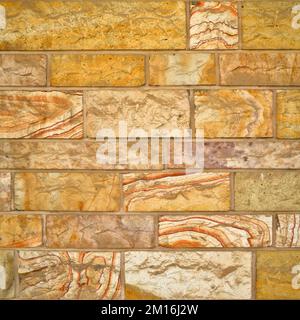 Robusto muro in pietra con taglio giallo e beige, ideale per sfondi, senza cuciture allineate Foto Stock