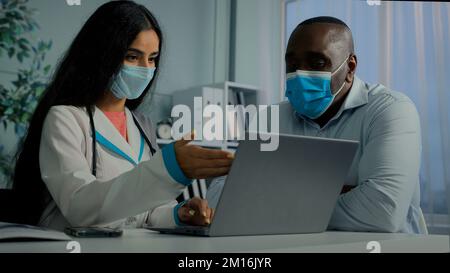 Donna medico e africano anziano paziente seduto in ospedale utilizzare laptop medico arabo spiegare elettronica tomografia risultato online test medico Foto Stock