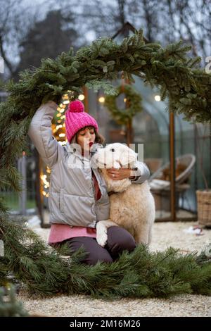 Donna con un cane nella corona di Natale in cortile Foto Stock