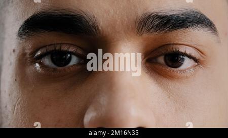 Estrema faccia primo piano giovane ispanico maschio occhi arabo con le sopracciglia marroni che lampeggiano guardando la macchina fotografica dimostrare la vista perfetta dopo oftalmol Foto Stock