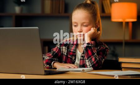 Stanco sonnolento bambino caucasico biondo piccolo pigro stanco ragazza studiare routine online lezione di istruzione elementare sul laptop napping a casa feeli Foto Stock