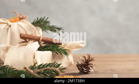 Zero spreco di natale concetto. Confezionato in tessuti naturali regali e decorazioni di materiali naturali su un tavolo grigio, spazio copia. Foto Stock