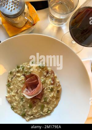 Risotto ai funghi porcini con prosciutto crudo e un bicchiere di vino rosso. Vista dall'alto. Foto Stock