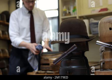 Il membro dello staff di Lock & Co Hatters usa Steam per rimodellare un cappello, Londra, Regno Unito. Foto Stock