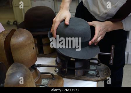 Il membro dello staff di Lock & Co Hatters usa Steam per rimodellare un cappello, Londra, Regno Unito. Foto Stock