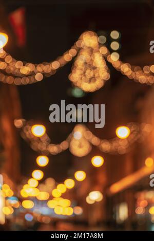 Strada notturna decorata con luci di vacanza, sfondo sfocato. Foto Stock